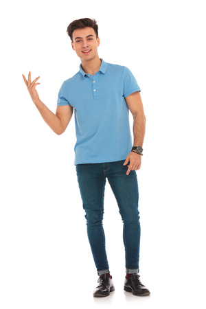 portrait of man in blue shirt pointing fingers while looking at the camera in isolated studio background