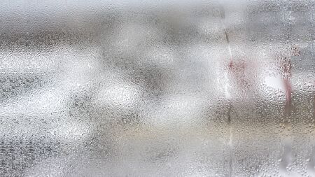 High humidity in the form of condensation on a transparent glass with large drops of natural water. defective plastic window with condensation