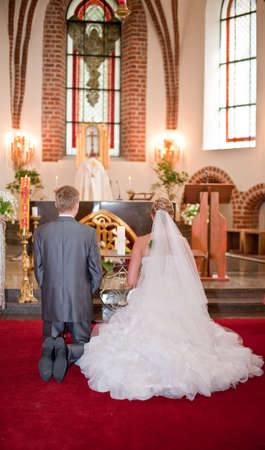Bride and groom kneeling on wedding ceremony in front of altar