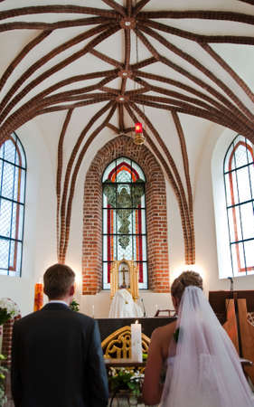 Bride and groom kneeling on wedding ceremony in front of altar