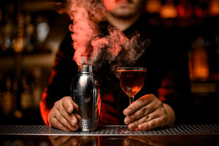 Smoking shaker and alcohol cocktail in bartenders hands Stock Photo