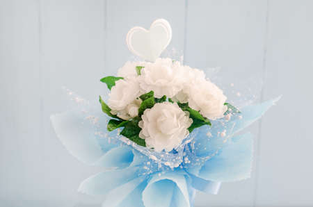 Artificial Jasmine flower bouquet with blue ribbon bow on white and blue wooden background - Jasmine is the symbol of Mothers Day in Thailand.