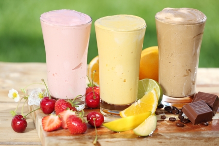 banana: Ba smoothies ngon với sữa chua hoặc kem trộn, hai thực hiện với trái cây và một trong sô cô la, cùng với nhiều trái cây tươi nhiệt đới trên bàn trong vườn