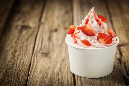 ice cream: Dâu tây nhiệt đới chín đỏ và vanilla ice cream joghurt đông lạnh cho một làm mới món tráng miệng mùa hè lạnh lành mạnh trong một bồn tắm takeaway trên một chiếc bàn gỗ mộc mạc cũ với copyspace