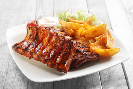 grilled pork: Đóng lên Dish Gourmet Main nướng sườn heo và khoai tây chiên trên trắng Plate. Phục vụ trên bảng gỗ.