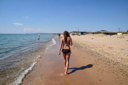 girl walking on the beach rear view walk the dark haired woman