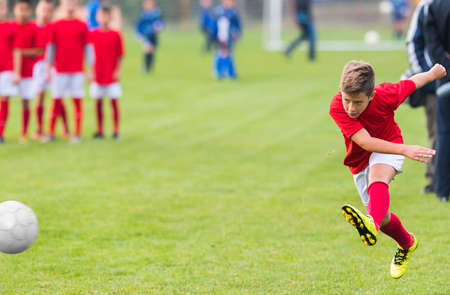 boy kicking soccer ball on sports field stock photo picture and