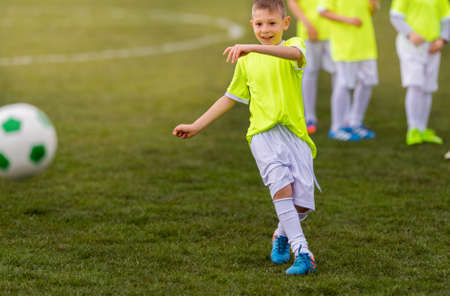 boy kicking football on the sports field during soccer match stock