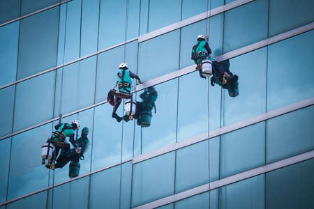 group of workers cleaning windows service on high rise building