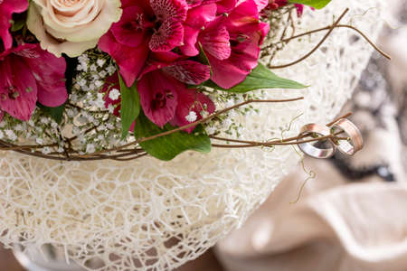close up on pair of rings on branch of bouquet with pink flowers