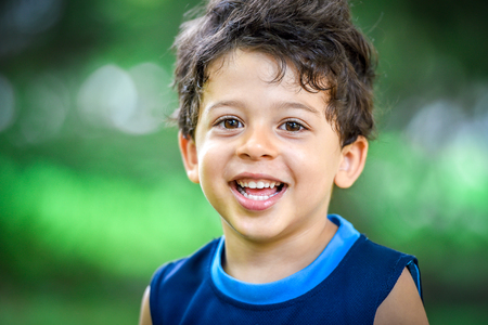 Happy mulatto boy child is smiling enjoying adopted life. Portrait of young boy in nature, park or outdoors. Concept of happy family or successful adoption or parenting.