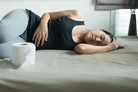 Asian woman with morning sickness and sleeping,Pregnant female nausea in bedroom,Indigestible