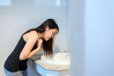 Asian woman have a morning sickness,Pregnant female nausea in toilet