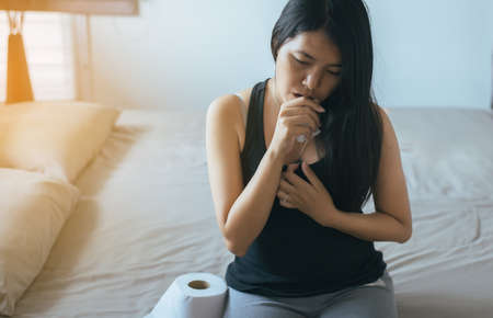 Asian woman have a morning sickness,Pregnant female nausea in bedroom