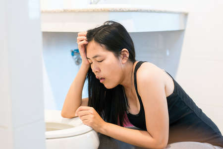 Asian woman with morning sickness,Pregnant female nausea in toilet Stock Photo