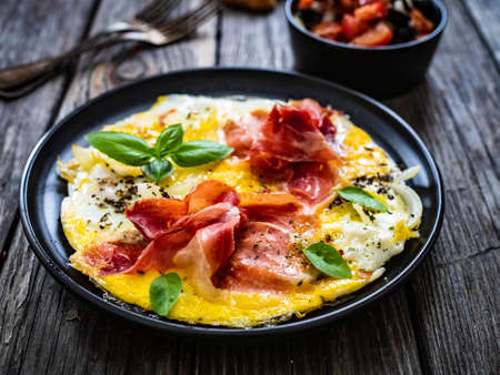 Petit déjeuner - oeufs brouillés avec jambon serrano et salade de légumes sur table en bois
