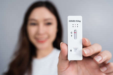 Happy woman holding coronavirus(covid-19) negative test result with antigen rapid test kit (atk)
