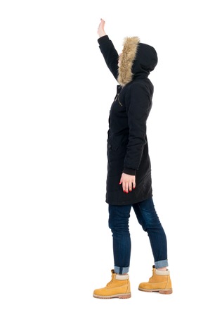 美しい女性歓迎を背面します 若い 10 代の女の子手を振るから リア人のコレクションを表示します 人の裏面表示 白い背景に分離されました 横と手を振って 暖かい冬の黒のジャケットの女の子が立っています の写真素材