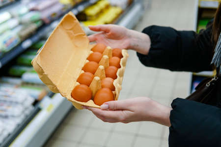 Une femme choisit des œufs de poule dans une épicerie. fermer. Banque d'images