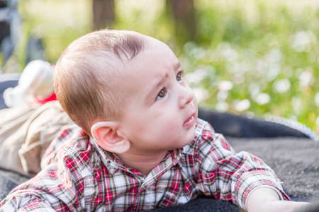 赤い格子縞のシャツとベージュのパンツで明るい茶色の髪でかわいい生後 6 ヶ月の赤ちゃんは好奇心だ 穏やかです の写真素材 画像素材 Image