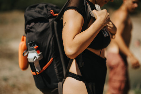 Young woman with backpack enjoying an outdoor hike with friends on a sunny day Foto de stock