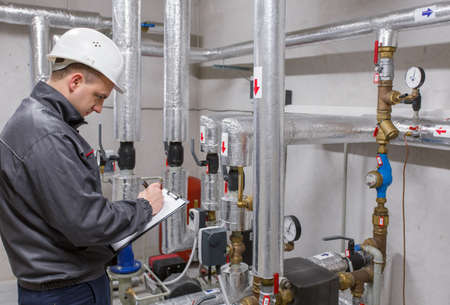 Plumbing Engineering Technician Inspecting Heating System In Boiler Room Plumbing Engineering Technician Inspecting Heating System In Boiler Room