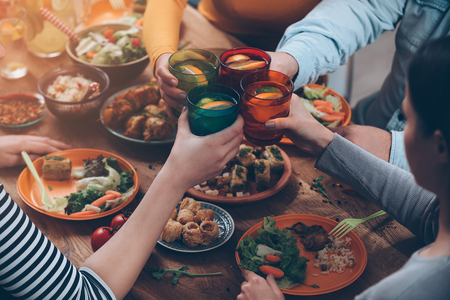 Cheers to us! Top view of people cheering with drinks while sitting at the rustic dining table - 49263807