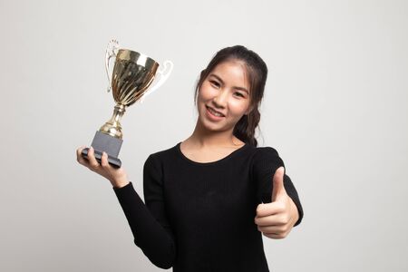 Successful young asian woman holding a trophy show thumb up on white background