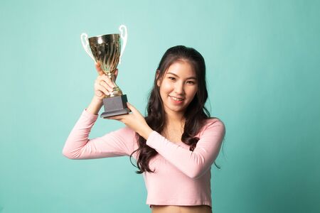 Successful young asian woman holding a trophy on cyan background Stock Photo