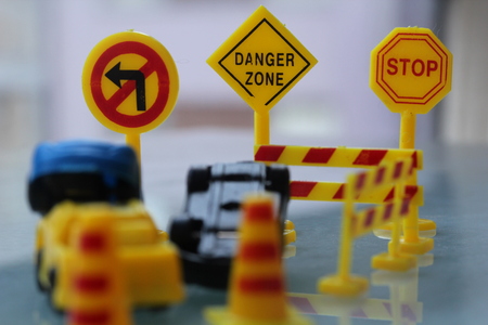 Car accident zone cordoned off with a yellow stop sign post two cars with a major collision with one car toppled by another brown car area cordoned by yellow barricades