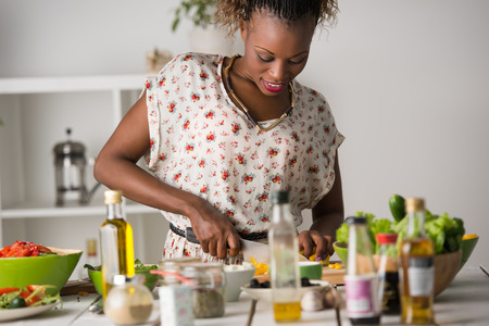 Jeune femme africaine cuisine. Aliments sains - Salade de légumes. Régime. Concept de régime Mode de vie sain. Cuisiner à la maison Préparer la nourriture