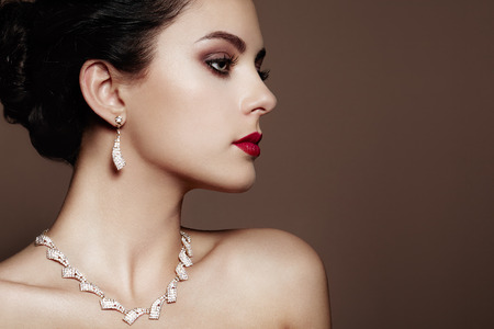 Fashion portrait of young beautiful woman with jewelry. Brunette girl. Perfect make-up. Beauty style woman with diamond accessories Фото со стока