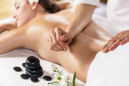 Massage: Молодая красивая женщина, наслаждаясь массажем на столе в спа-центре