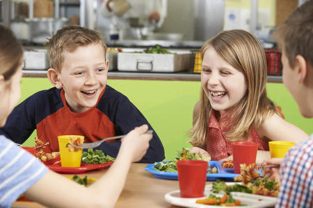 Gruppe Schüler, die bei Tisch in der Schulcafeteria isst Mahlzeit sitzen