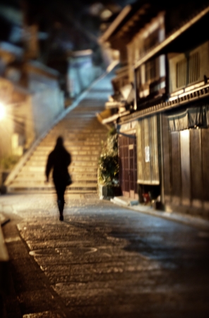sad lonely: Woman walking alone along a cobblestone road at night in Kyoto, Japan Stock Photo