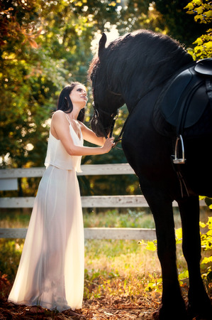 señora de moda con el vestido de novia blanco cerca de caballo
