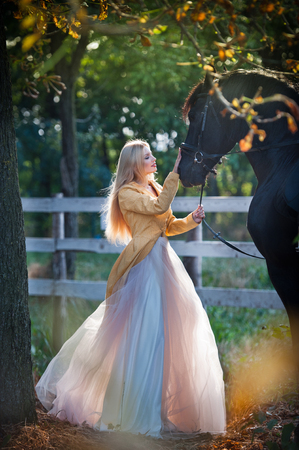 señora de moda con el vestido de novia blanco cerca de caballo