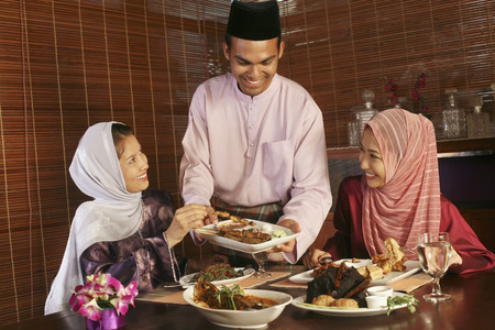 Man passing a plate of satay to his friends - 39064411