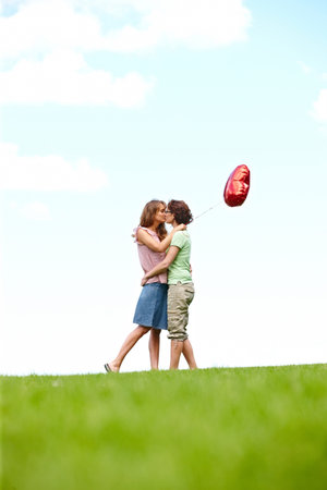 Two women kissing with balloon Stock Photo