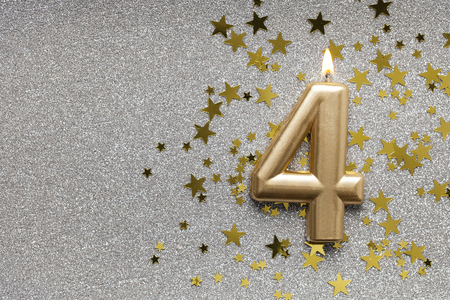 Number 4 gold celebration candle on star and glitter background