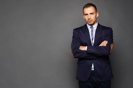 149102298-confident-businessman-in-suit-isolated-at-dark-background-a-handsome-young-man-in-an-official-outfit.jpg