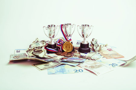 Sport winning concept: three cups among diverse currencies euro,
