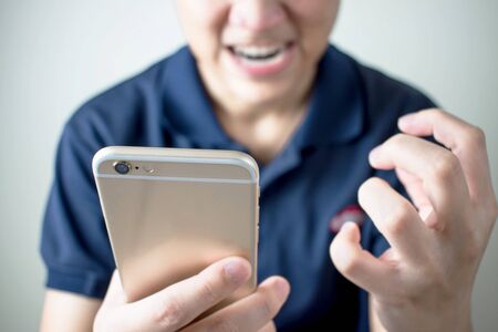 Asian people are angry from the message on the smartphone in the room.