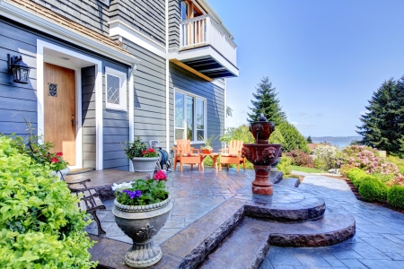 Front of the blue luxury house exterior with fountain and nice landscape