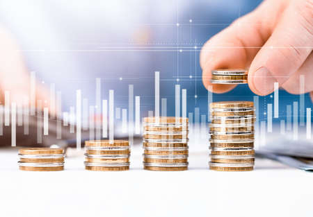 Man stacks coins in columns, double exposure with graph and diagram. concept of counting savings