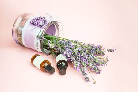 Kosmetyki naturalne. świeże kwiaty lawendy i butelki olejku eterycznego lub serum na pastelowym różowym tle. alternatywna medycyna domowa. zbliżenie, styl vintage. Zdjęcie Seryjne