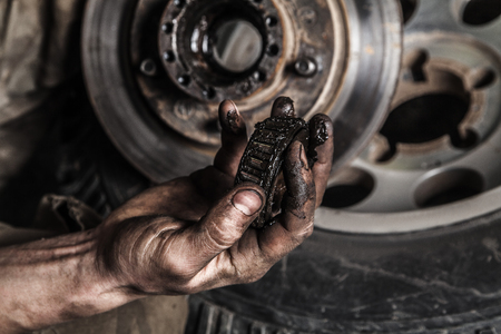Dirty man hand with gear and car wheel Фото со стока