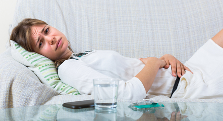 Miserable young woman with early term pregnancy having miscarriage