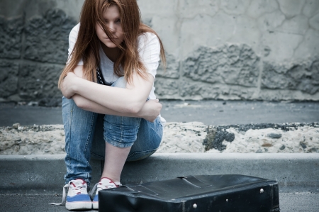 sad lonely: Beautiful young sad girl sitting on asphalt. Photo in cold faded tones