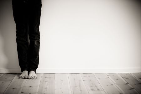 sad lonely: Legs and bare feet of boy leaning against wall